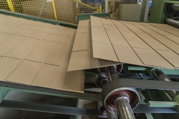 Kartonnen platen worden op maat gesneden en gevouwen op een productielijn in de fabriek.
